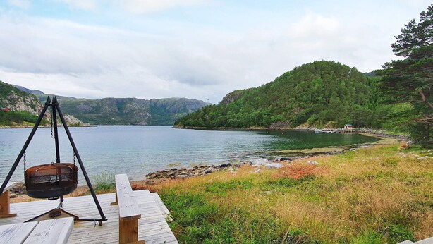 A wooden deck with a swing, overlooking a lake with a forested shoreline. - 6 Person Holiday Home in Sundlandet (Hitra)
