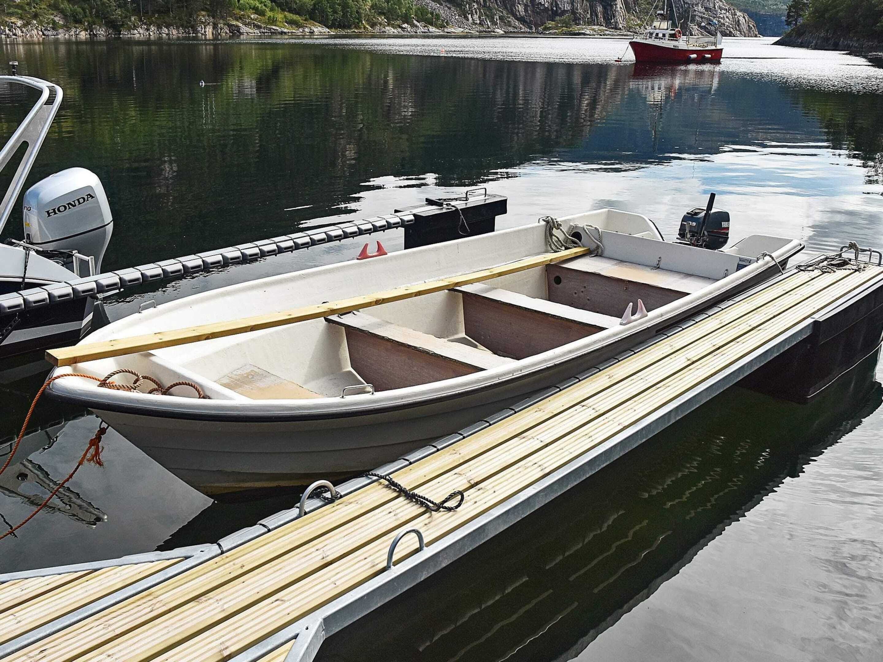 A small motorboat docked at a pier with a wooden deck, a motor, and a life preserver visible.