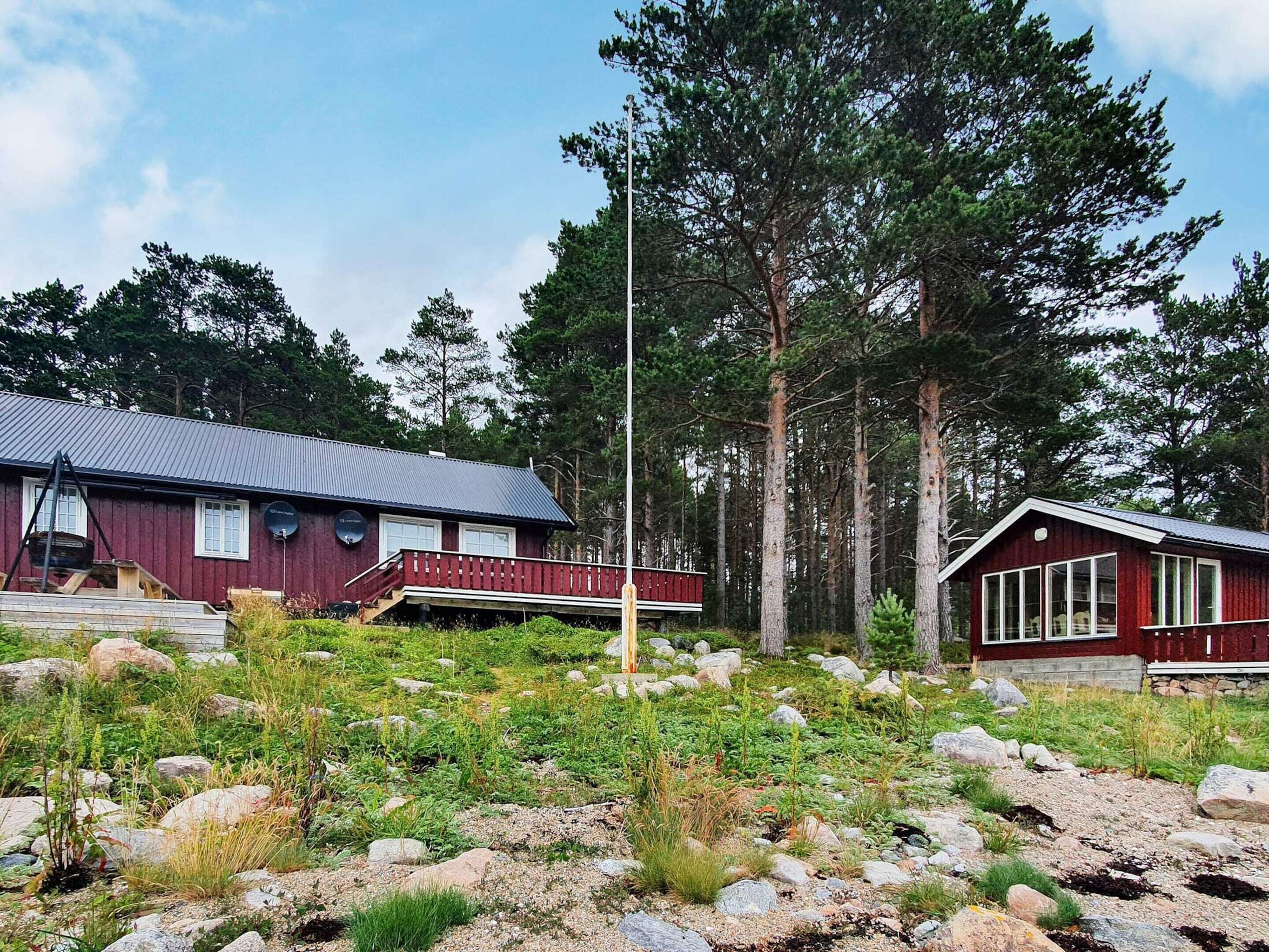 A cabin with a metal roof, a red exterior, and a deck.