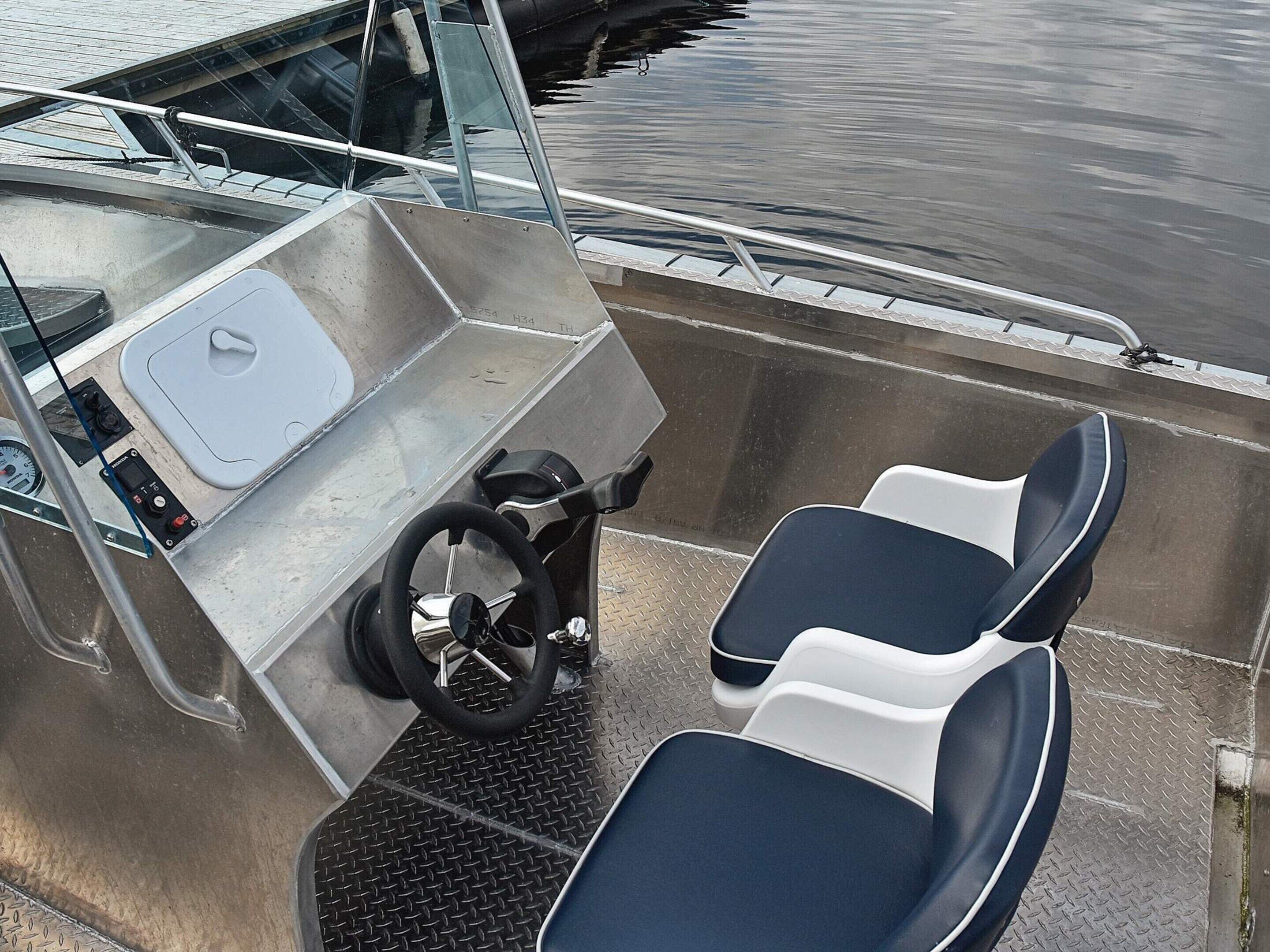 A boat's control station with a steering wheel, two seats, and a control panel.