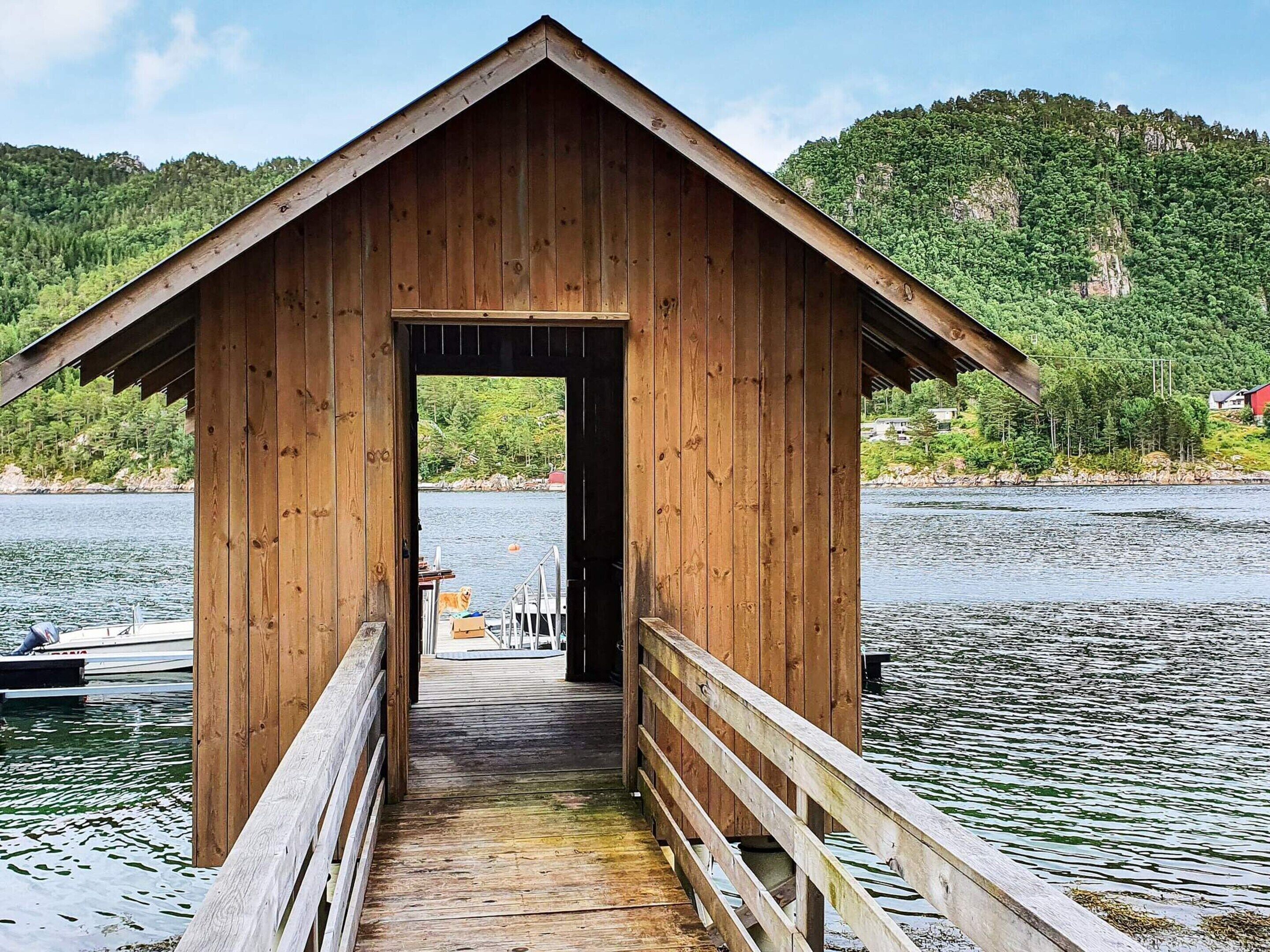 A wooden boathouse with a wooden deck leading to a dock.