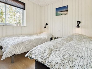 A room with two beds, a window with blinds, a wall-mounted picture, and a wall lamp. - 5 Star Holiday Home in Liseleje (Liseleje)