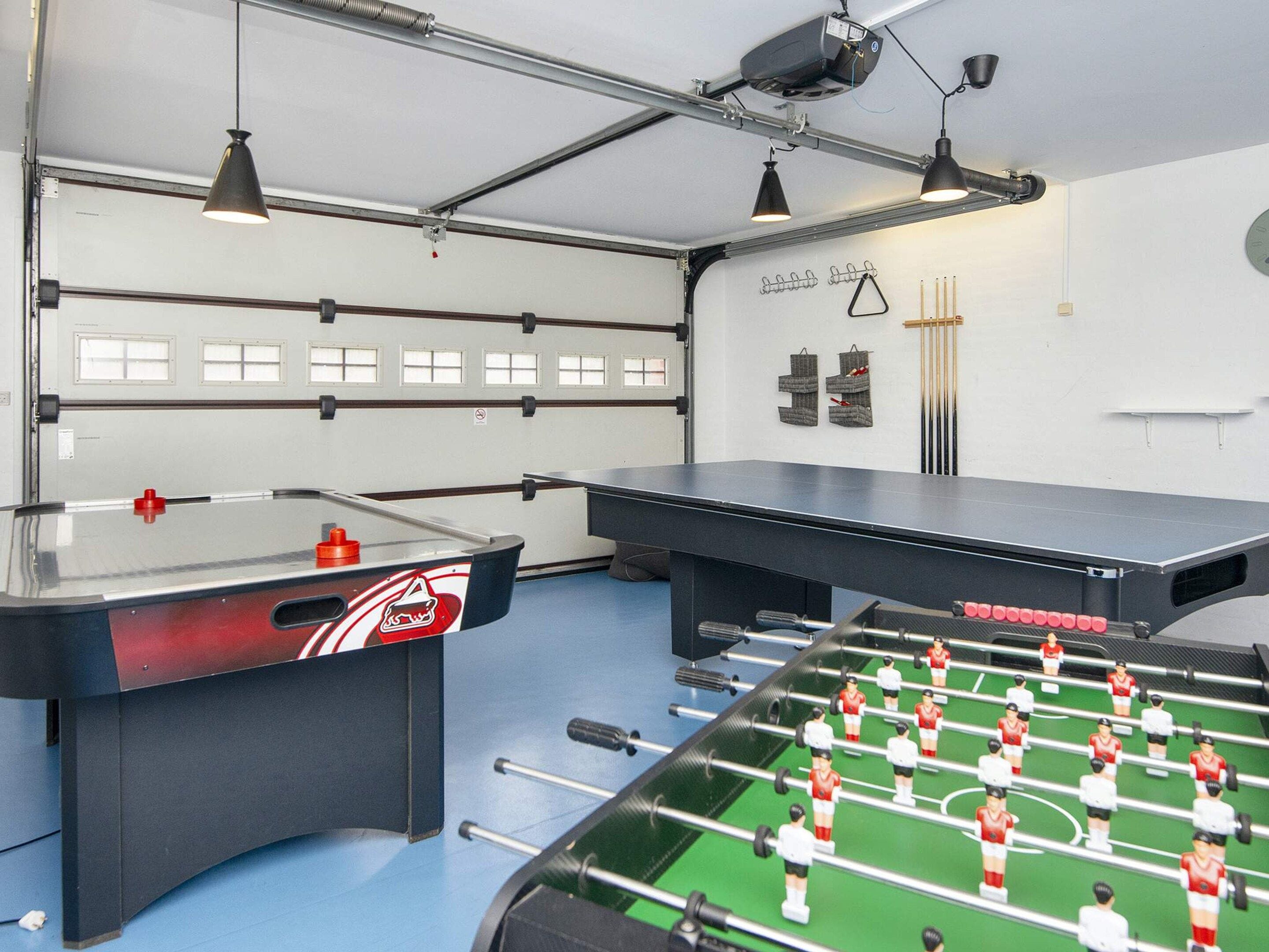 A room with two foosball tables, a ping pong table, and a billiards table.