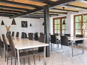 A conference room with a long table, chairs, pendant lights, and large windows.