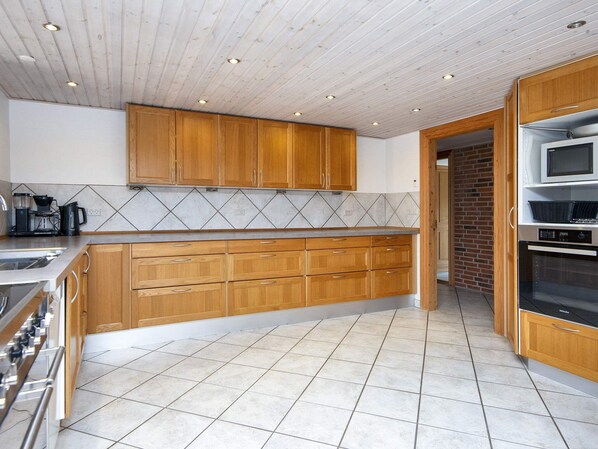 Eine Küche mit Holzschränken, einem Edelstahlherd und einer gefliesten Spritzschutzwand.