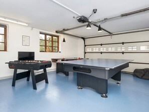 Une pièce équipée d’un baby-foot, d’une table de ping-pong et d’un ventilateur de plafond.