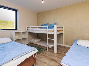 A room with bunk beds, a window, and a desk.