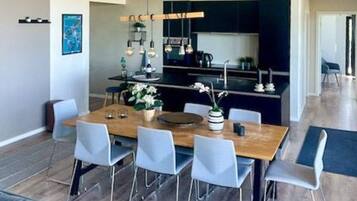 A modern dining area with a wooden table, six chairs, and hanging pendant lights.