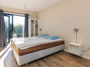 A bedroom with a bed, a white bedside table, a wall-mounted lamp, and a built-in shelving unit. - 8 Person Holiday Home in Olsted-by Traum (Olsted)