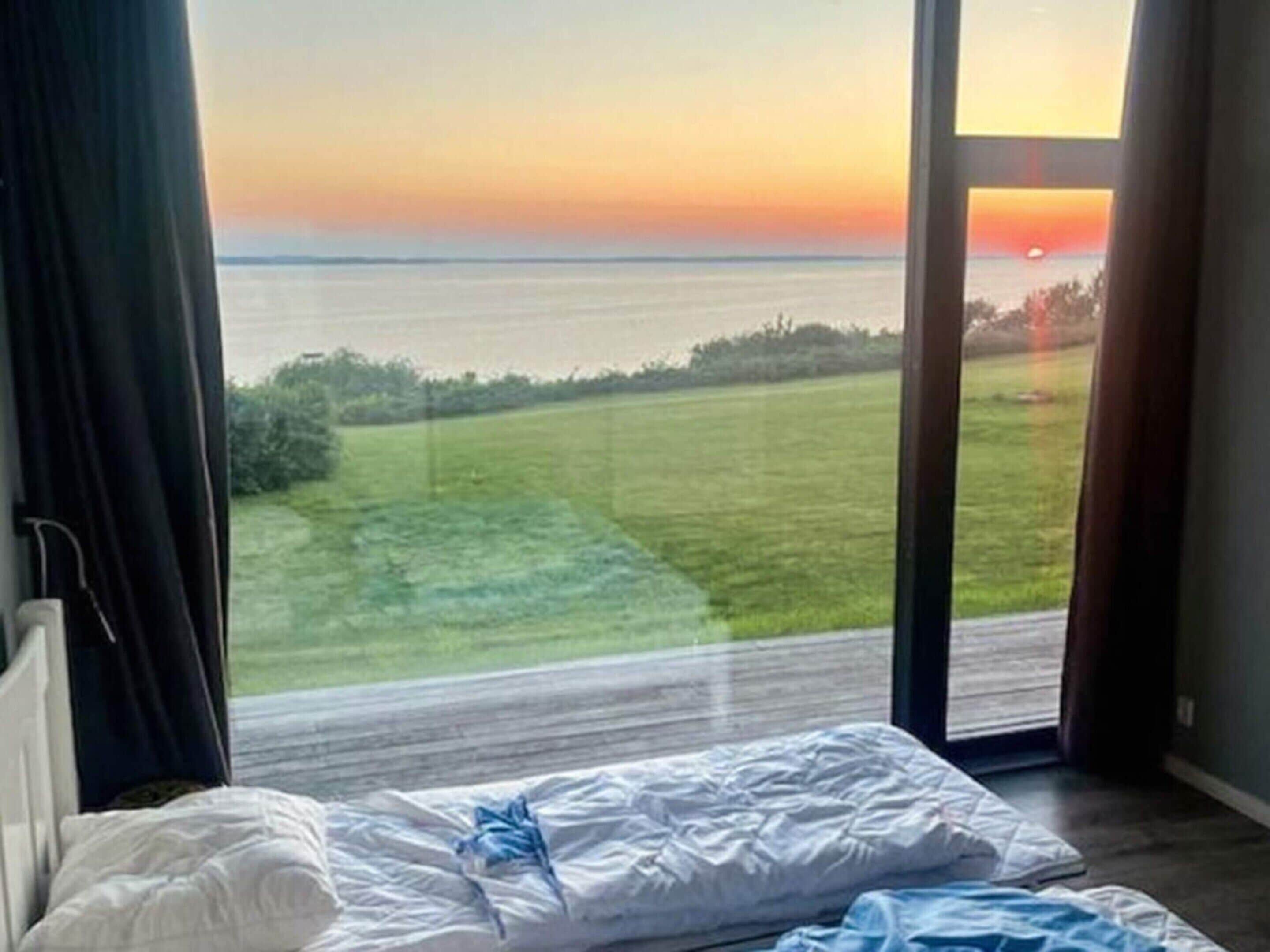 A bedroom with a view of the sea and a grassy area.