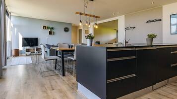 A modern kitchen with a large island, built-in appliances, and pendant lighting.