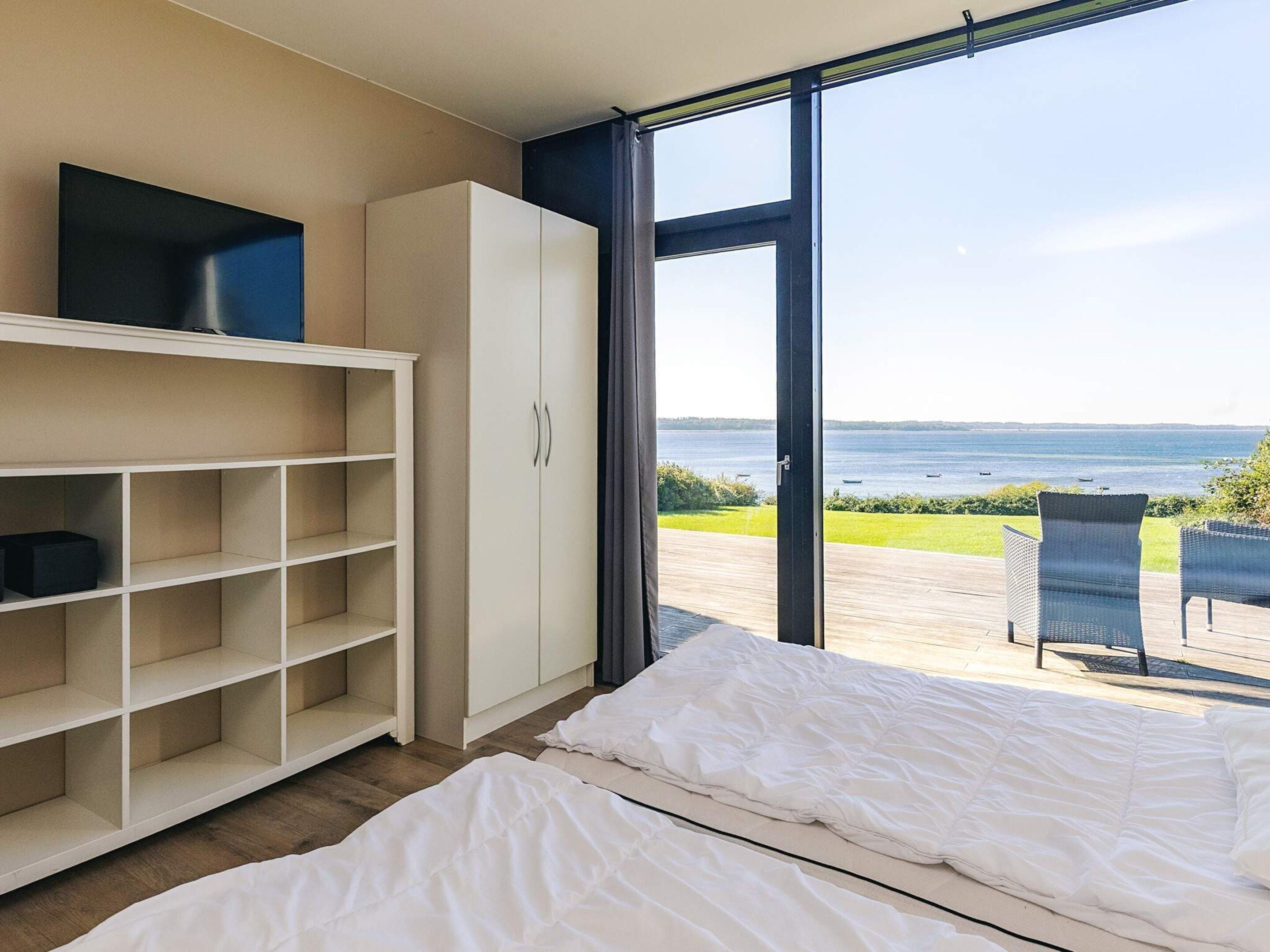 A bedroom with a bed, a wardrobe, and a view of the sea.