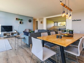A modern living room with a dining area, a television, and a kitchen in the background. - 8 Person Holiday Home in Olsted-by Traum (Olsted)