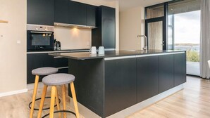 A modern kitchen with a central island, bar stools, and a large window offering a view. - 8 Person Holiday Home in Olsted-by Traum (Olsted)