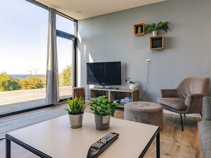 Una sala de estar moderna con televisión, asientos y plantas en macetas.
