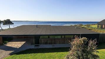 A modern building with a flat roof overlooking a body of water.