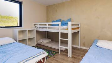A room with bunk beds, a window, and a desk.