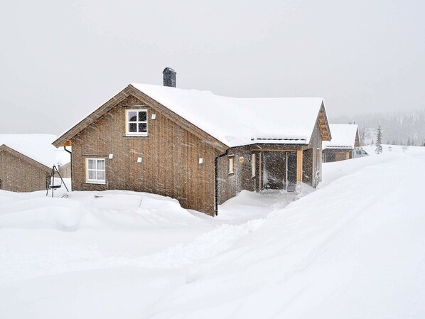 A wooden cabin with a snow-covered roof and a chimney, surrounded by a snowy landscape. - 13 Person Holiday Home in Øyer (Øyer)