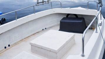 L'intérieur d'un bateau, avec un pont blanc, un coffre de rangement noir et des garde-corps en métal.