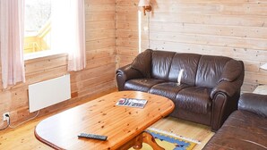 A wooden-paneled room with a brown leather sofa, a wooden coffee table, and a lamp.