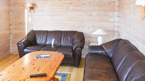 A room with two leather sofas, a wooden coffee table, and a lamp.