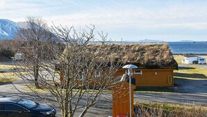 A small wooden cabin with a thatched roof, a satellite dish, and a red bucket.