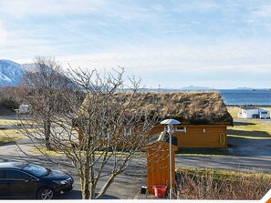 A small wooden cabin with a thatched roof, a satellite dish, and a red bucket. - 6 Person Holiday Home in Aukra (Aukra)