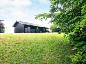 A single-story building with a dark exterior, a flat roof, and a grassy yard.