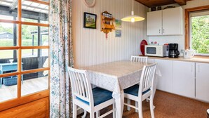 A cozy kitchen with a dining table, chairs, a clock, and a microwave.