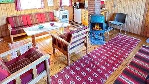 A cozy cabin interior with a wooden interior, a fireplace, a sofa, a dining table, and a kitchen area. - 5 Person Holiday Home in Farsund (Farsund)