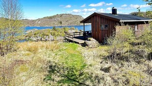 A wooden cabin with a dock, overlooking a lake and hills. - 5 Person Holiday Home in Farsund (Farsund)
