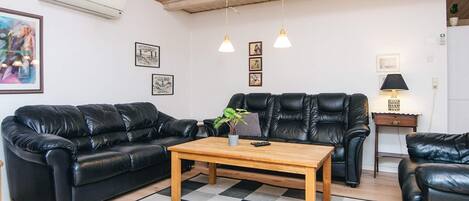 A modern living room with a black leather sofa, a wooden coffee table, and a checkered rug.