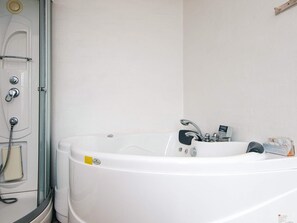 A modern bathroom with a large bathtub, a shower, and a toilet.