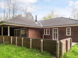 A wooden house with a tiled roof, a chimney, and a wooden fence.