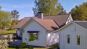 A single-story white house with a red-tiled roof, a front porch, and a small garden area. - Holiday Home in Lerum (Lerum)