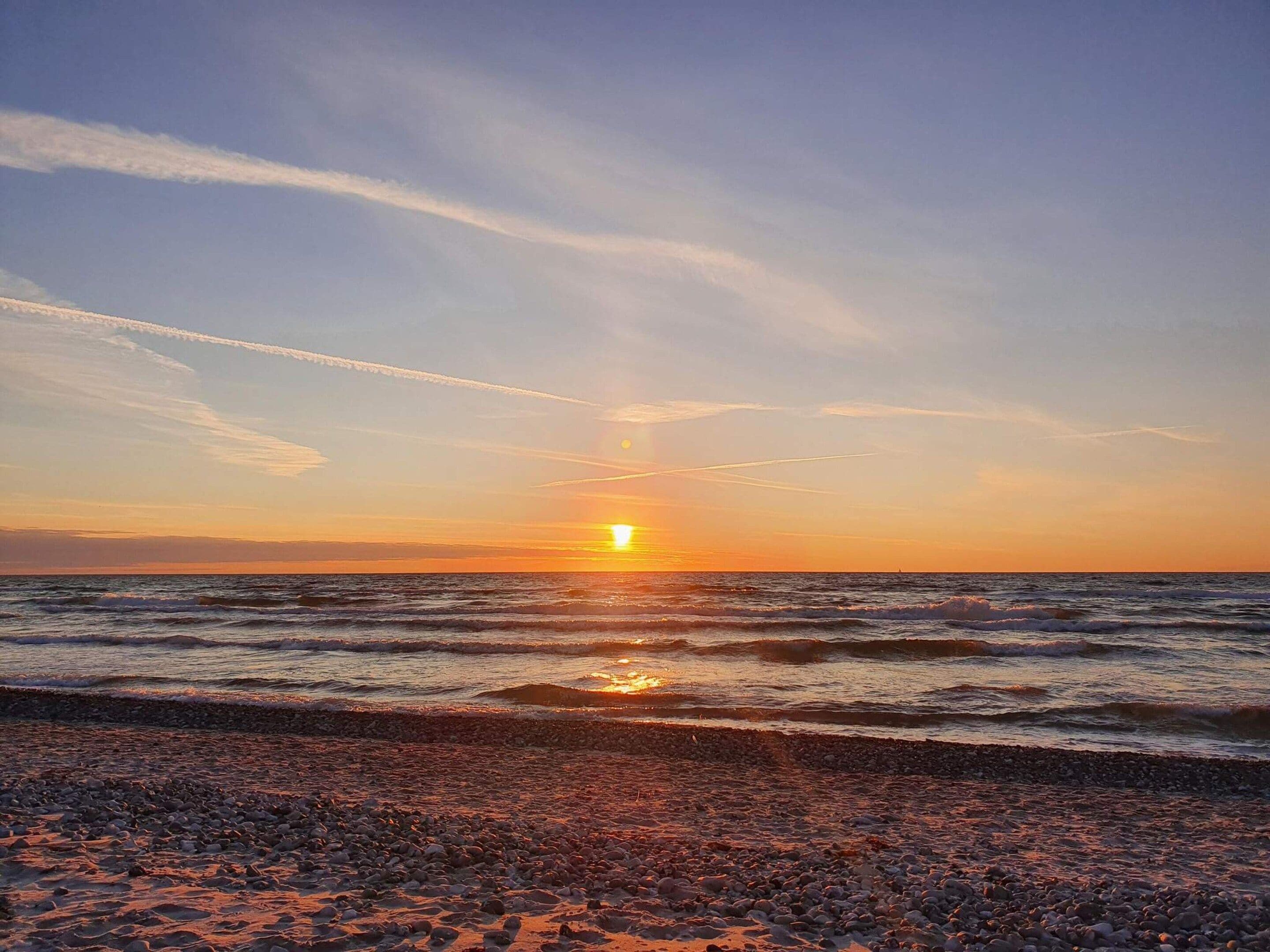 Ein Sonnenuntergang über einem felsigen Strand mit Wellen.