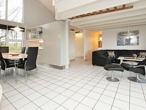 A modern living space with a dining area, a black leather sofa, and a kitchen area. - 10 Person Holiday Home in Ebeltoft-by Traum (Ebeltoft)