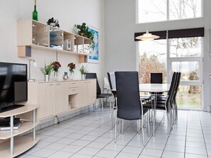 A modern kitchen with a dining area, featuring a large window, a TV, and various kitchen appliances. - 10 Person Holiday Home in Ebeltoft-by Traum (Ebeltoft)