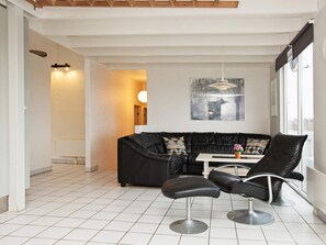 Un interior moderno con un sofá de cuero negro, dos sillones de cuero negro, una mesa blanca y un ventanal grande.