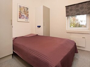 A bedroom with a bed, a window with a view, a radiator, and a painting on the wall. - 10 Person Holiday Home in Ebeltoft-by Traum (Ebeltoft)