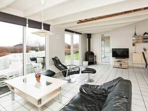 A modern living room with a sofa, a dining table, and a TV. - 10 Person Holiday Home in Ebeltoft-by Traum (Ebeltoft)