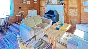 Ein gemütliches Blockhaus-Interieur mit einer Couch, einem Esstisch und einem Kamin.