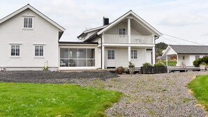 A two-story white house with a balcony, a covered porch, and a gravel driveway. - Holiday Home in Tornes I Romsdal (Hustadvika)