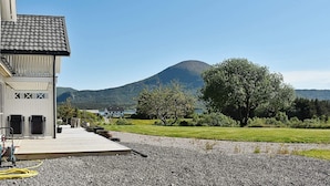 A building with a wooden deck, a mountain in the background, and a clear sky. - Holiday Home in Tornes I Romsdal (Hustadvika)
