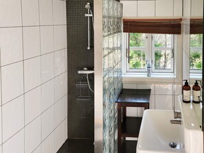 Une salle de bain avec une douche, un lavabo et une fenêtre.