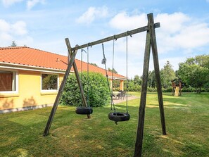 A wooden swing set with two tire swings in a backyard.