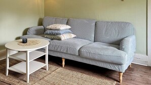 A cozy living room with a striped sofa, a small round table, and a woven rug. - Holiday Home in Vargön (Västra Tunhem)