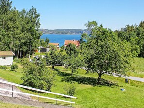 A residential area with houses, a grassy field, and a body of water in the background. - 6 Person Holiday Home in Brastad (Brastad)