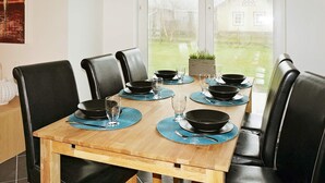 Mesa de jantar com cadeiras pretas, jogos americanos azuis e tigelas pretas.