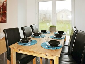 A dining table with black chairs, blue placemats, and black bowls. - Holiday Home in Falkenberg (Glommen)
